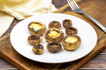 Baked mushrooms in a ceramic plate on a wooden background. Cultivated mushroom or portabello mushroom