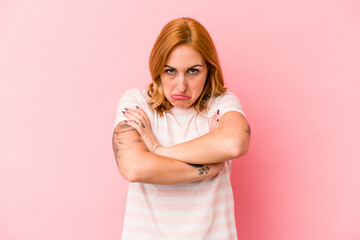 Young caucasian woman isolated on pink background shrugs shoulders and open eyes confused.