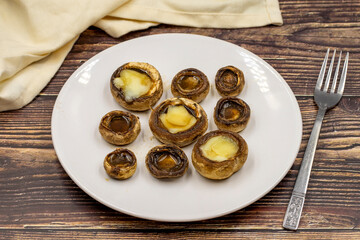 Baked mushrooms in a ceramic plate on a wooden background. Cultivated mushroom or portabello mushroom