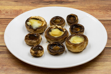 Baked mushrooms in a ceramic plate on a wooden background. Cultivated mushroom or portabello mushroom