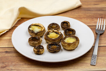 Baked mushrooms in a ceramic plate on a wooden background. Cultivated mushroom or portabello mushroom