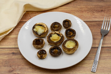 Baked mushrooms in a ceramic plate on a wooden background. Cultivated mushroom or portabello mushroom