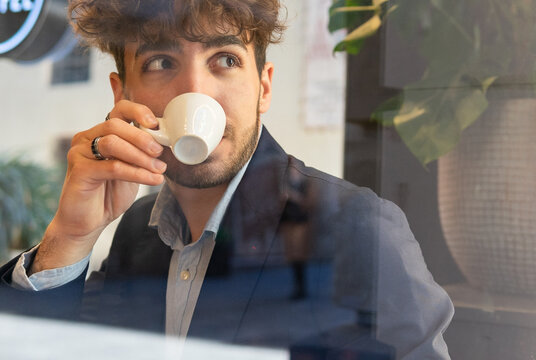 Through glass of Hispanic man drinking coffee