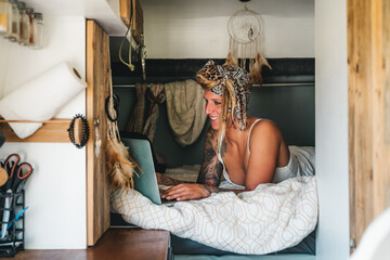 Cheerful hippie woman browsing laptop in van