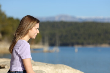 Happy teen contemplating a lake view in nature