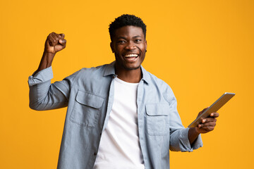 Happy african american guy sharing success, using pad