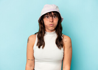 Fototapeta premium Young Argentinian woman isolated on blue background blows cheeks, has tired expression. Facial expression concept.