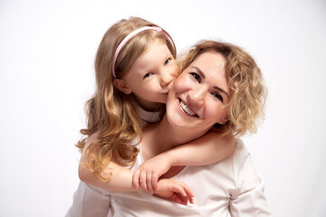 Nice mom and beautiful blonde daughter in room of the studio durin spring photo shoot before easter. Happy girl and woman together