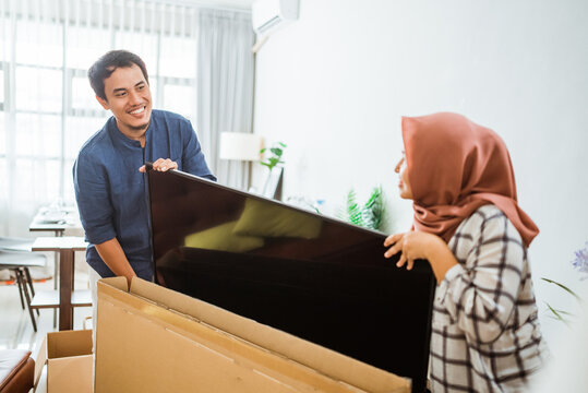 Excited Couple Setting Up New Television At Home