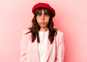 Young Argentinian woman isolated on pink background blows cheeks, has tired expression. Facial expression concept.