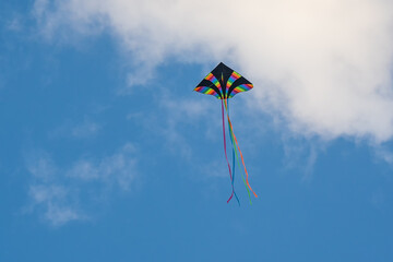 Colorful kite flying, soaring against a blue sky