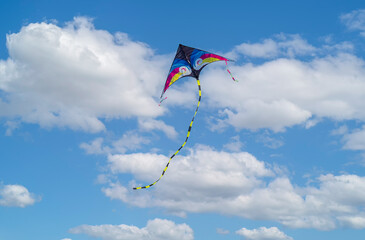 Colorful kite flying, soaring against a blue sky.