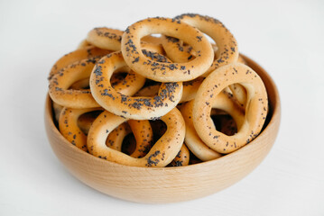 Dried bagels with poppy seeds in a wooden bowl on a white background