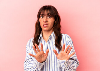 Young Argentinian woman isolated on pink background rejecting someone showing a gesture of disgust.