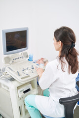 Female diagnostician examining patient using ultrasonic equipment