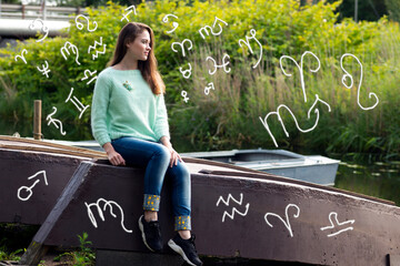 Woman resting in nature around astrological symbols

