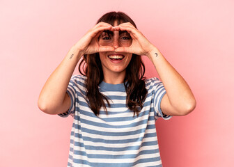 Young Argentinian woman isolated on pink background showing okay sign over eyes