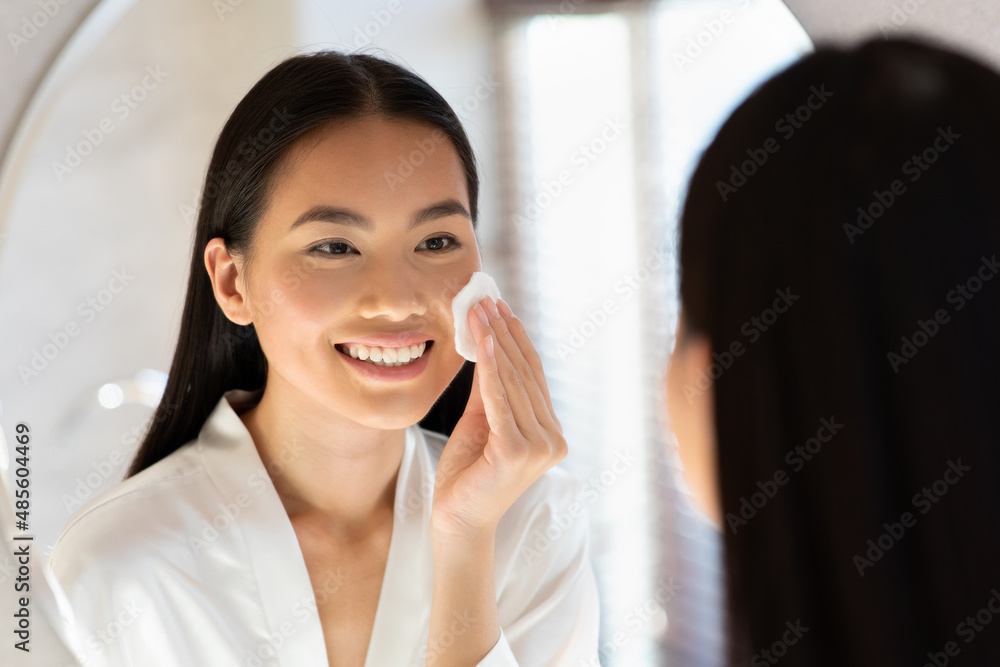 Wall mural Mirror reflection of pretty asian woman using tonner