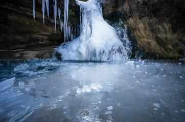 frozen waterfall over iced river in winter, campdevenol spain © Diego