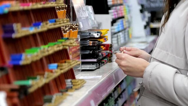 A young girl artist chooses pencil in an art store.