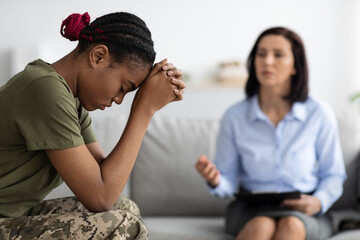 Posttraumatic stress disorder. Depressed black soldier woman attending therapy session with...