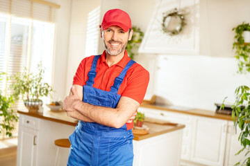 Smiling handsome plumber, repairman looking at camera in the kitchen. Handyman.