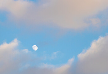 Beautiful shot of white clouds and a small moon on the sky