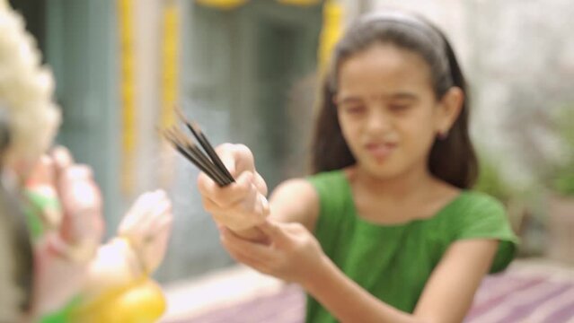 focus on hand. indian teenger devotee praying god by offering insane or agara batti sticks during ganesh festival - concept of reverence, hindu tredition rituals and cultures.