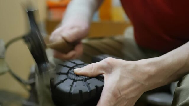 The shoemaker taps the sole of his shoe with a hammer. Professional used shoe repair. Slow motion. close-up