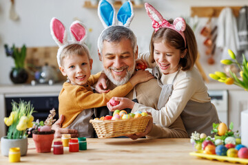 Happy family grandfather and cute grandchildren with Easter basket full of painted colorful eggs