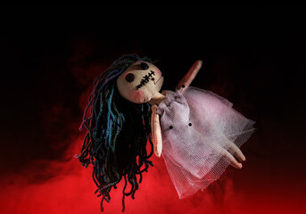 Female voodoo doll with pins and smoke on dark background