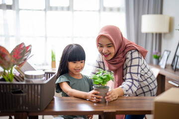 muslim mother and daughter decorating her house with indoor plants