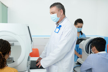 Obraz premium Optometrists checking eyesight of patients in clinic with modern equipment