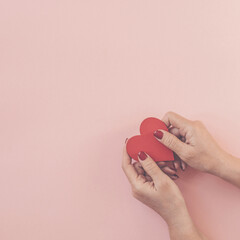Fototapeta na wymiar Woman hands holding heart on pink background.