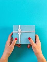 Woman hands holding gift, blue background.