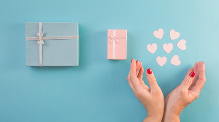 Gift boxes and hearts, woman hand, blue background.