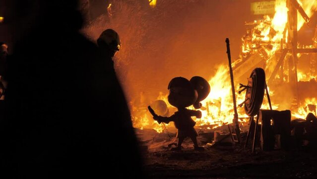 Firefighter burning ninots in the fire of La Cream on Fallas celebration, Spain