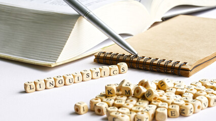 Word linguistics next to an open book, notepad, pen and many letters. Concept of the study of the...