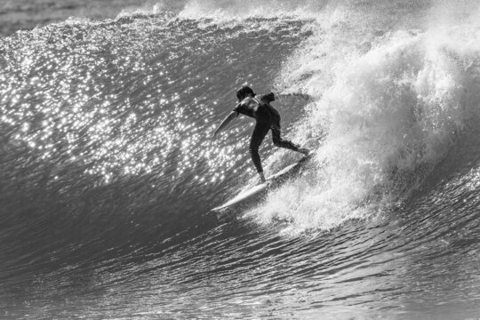 Surfing Surfer Rides Light Reflecting Wave Rear Action Black and White Photo.