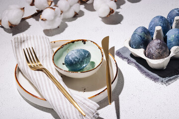 Blue Easter eggs on a white concrete background. Table setting for easter holidays