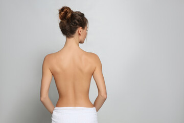 Back view of woman with perfect smooth skin on light grey background, space for text. Beauty and...