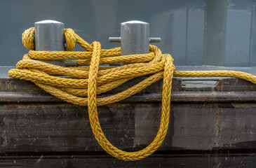 Closeup of a pair of shipboard bitts and a yellow mooring line.  