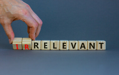 Relevant or irrelevant symbol. Businessman turns wooden cubes changes the word irrelevant to relevant. Beautiful grey table grey background. Business, relevant or irrelevant concept. Copy space.