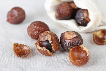 Soap berries or soap nuts in a cotton bag on a gray color cotton background close up. Dried Sapindus Mukorossi shells.