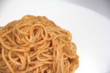 Boiled spaghetti mixed with tomato. On a white background.