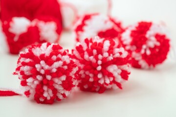 Close up red and white yarn strains of pompoms balls as martenitsa, bulgarian folklore tradition in March Baba Marta day. Shallow depth of focus. Colorful yarn texture background.