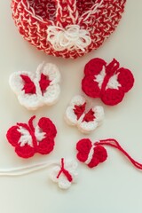 Martenitsa, white and red strains of yarn, Bulgarian folklore tradition, welcoming the spring in March, adornment symbol. Crochet colorful butterfly. Shallow depth, white background. Baba Marta Day.