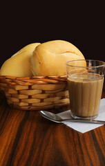 Coffee and milk glass with basket bread on the wooden table. Brazilian breakfast.