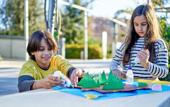 children doing crafts at a table in the park