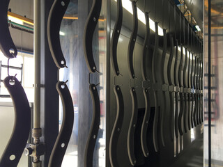 Powder coating line. Metal panels are suspended on an overhead conveyor line. Painting products in...